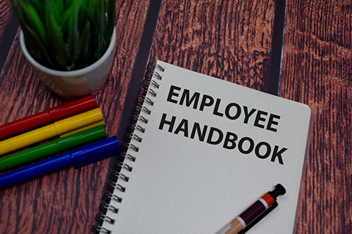 Employee handbook next to colored pens and plant